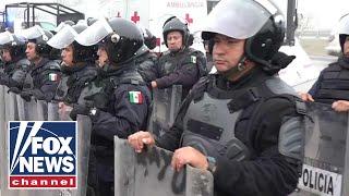 Mexican police in riot gear line up at US border